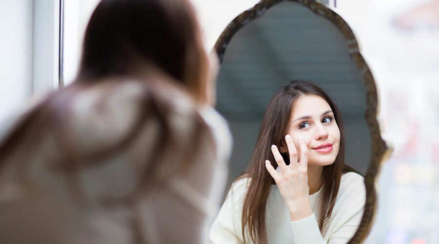 Mulher jovem na frente do espelho com melasma.