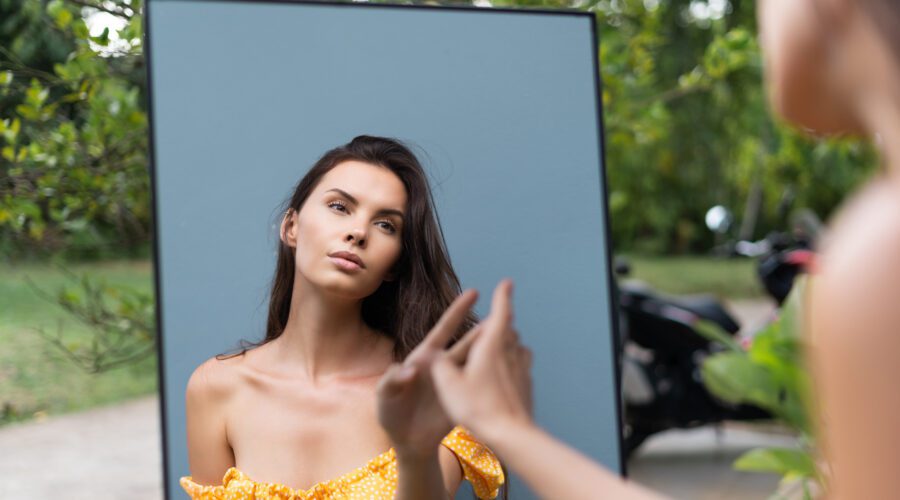 Mulher com vestido amarelo, em frente ao espelho