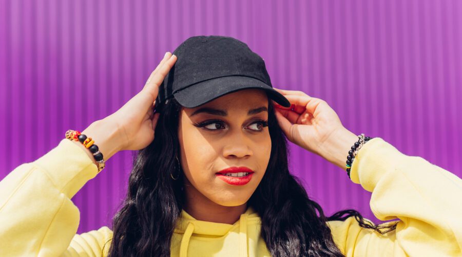 Mulher jovem, maquiada de boné preto.