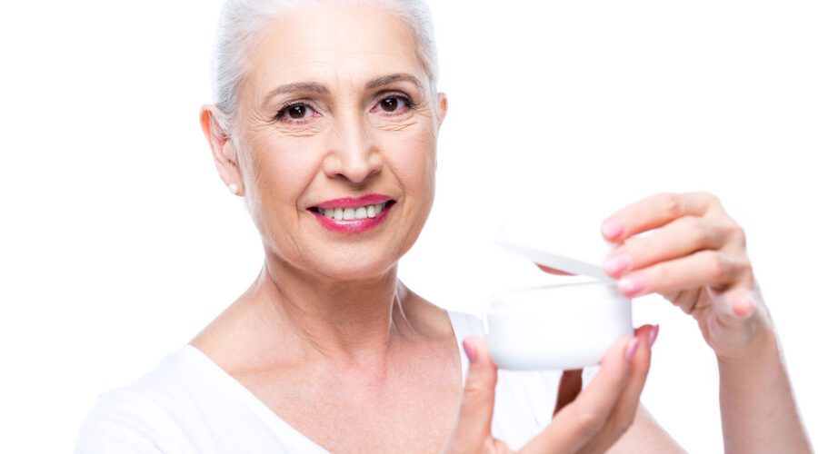 Mulher idosa com pele bonita passando creme de anti-idade