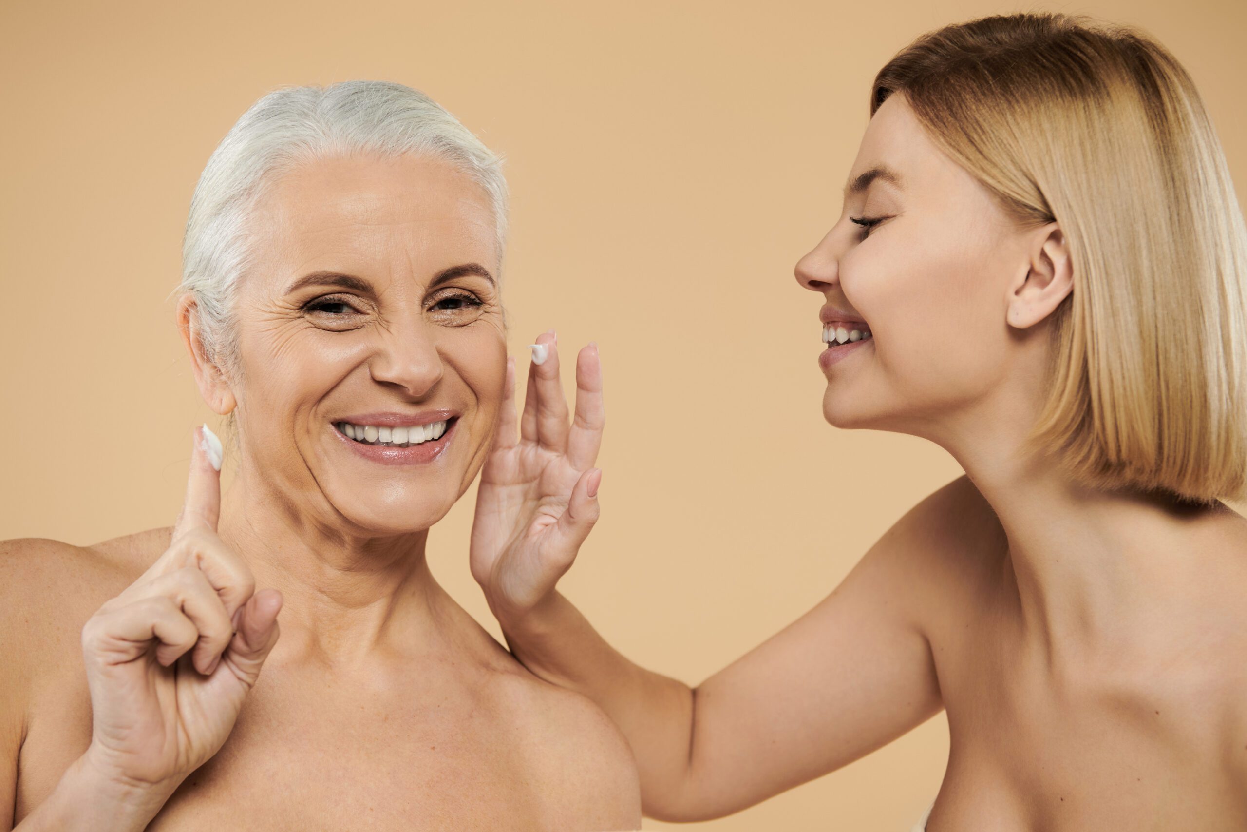 Duas mulheres de idades diferentes passando creme no rosto.