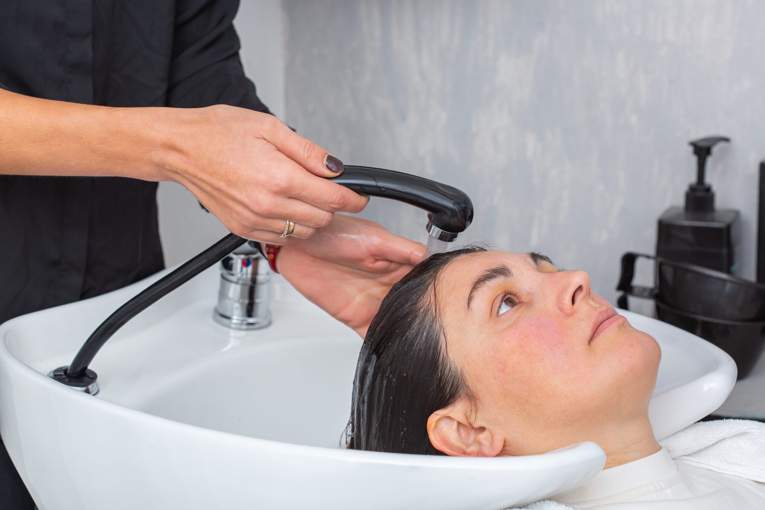 Cabeleireiro lavando o cabelo para uma jovem cliente